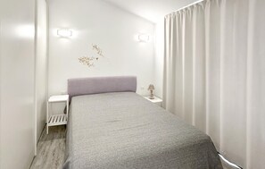 Une chambre à coucher comprenant un lit, une table de chevet, une lampe et un luminaire fixé au mur.