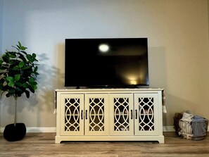A television on a cabinet with a plant beside it.