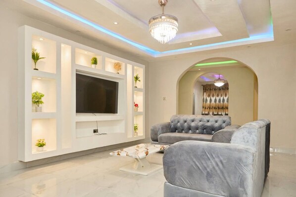 Un soggiorno moderno con una televisione a schermo piatto, divani in tessuto grigio e un'elegante porta ad arco decorativa.