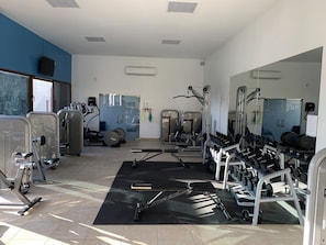 Ein Fitnessstudio mit unterschiedlichen Trainingsgeräten, darunter Laufbänder, Kraftgeräte und Kurzhanteln.