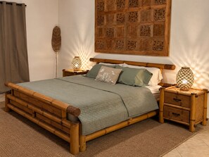 Ein Bett mit Holzrahmen, einer grünen Tagesdecke und zwei Nachttischen mit Lampen.