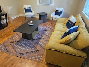 A living room with a sofa, two chairs, a coffee table, and a patterned rug. - Pershing Park Retreat (Montgomery)