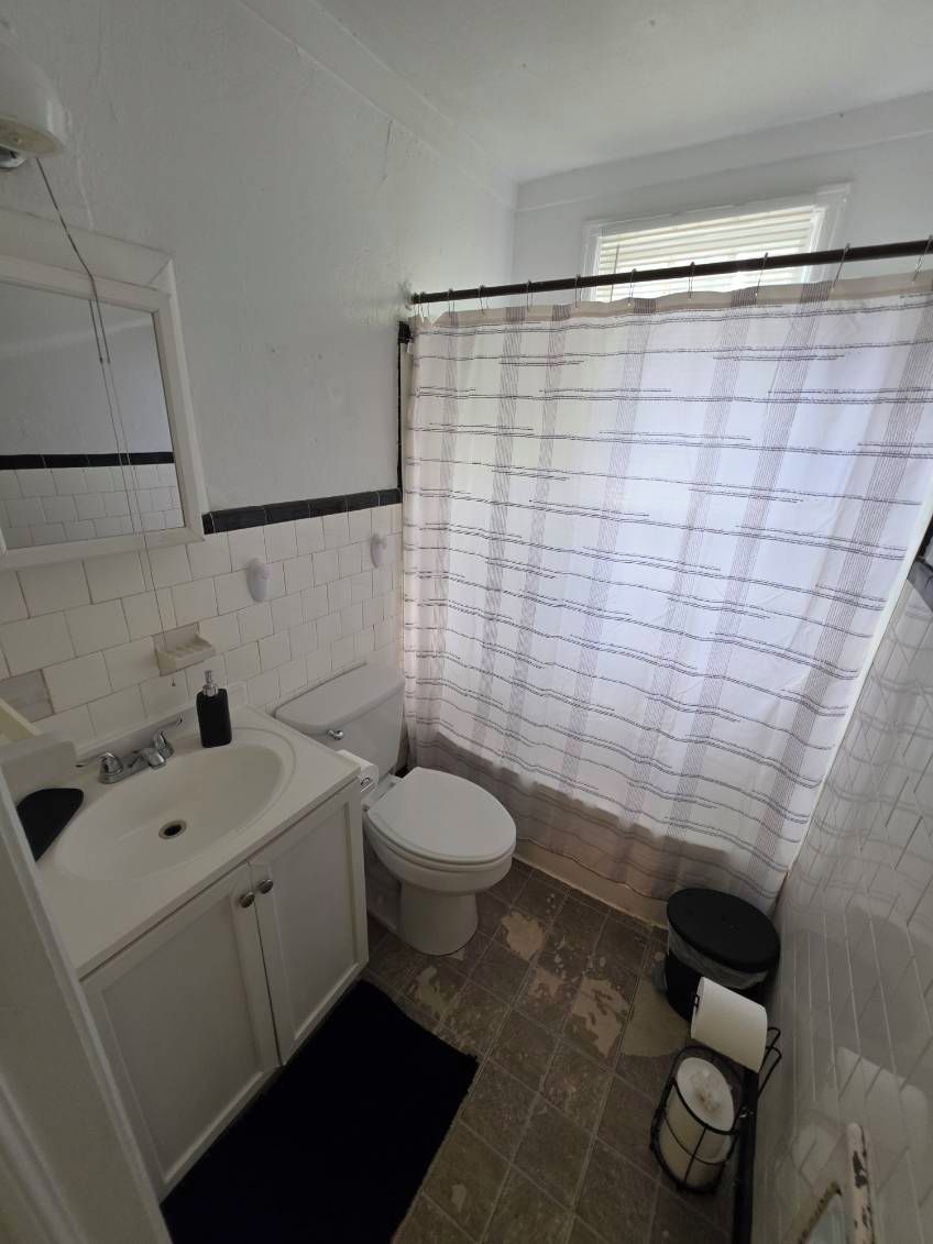 Un baño con lavamanos blanco, inodoro y cortina de ducha.