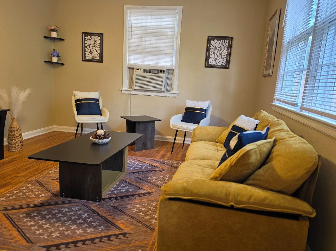 Un salon comprenant un canapé, deux fauteuils, une table basse et un tapis à motifs.