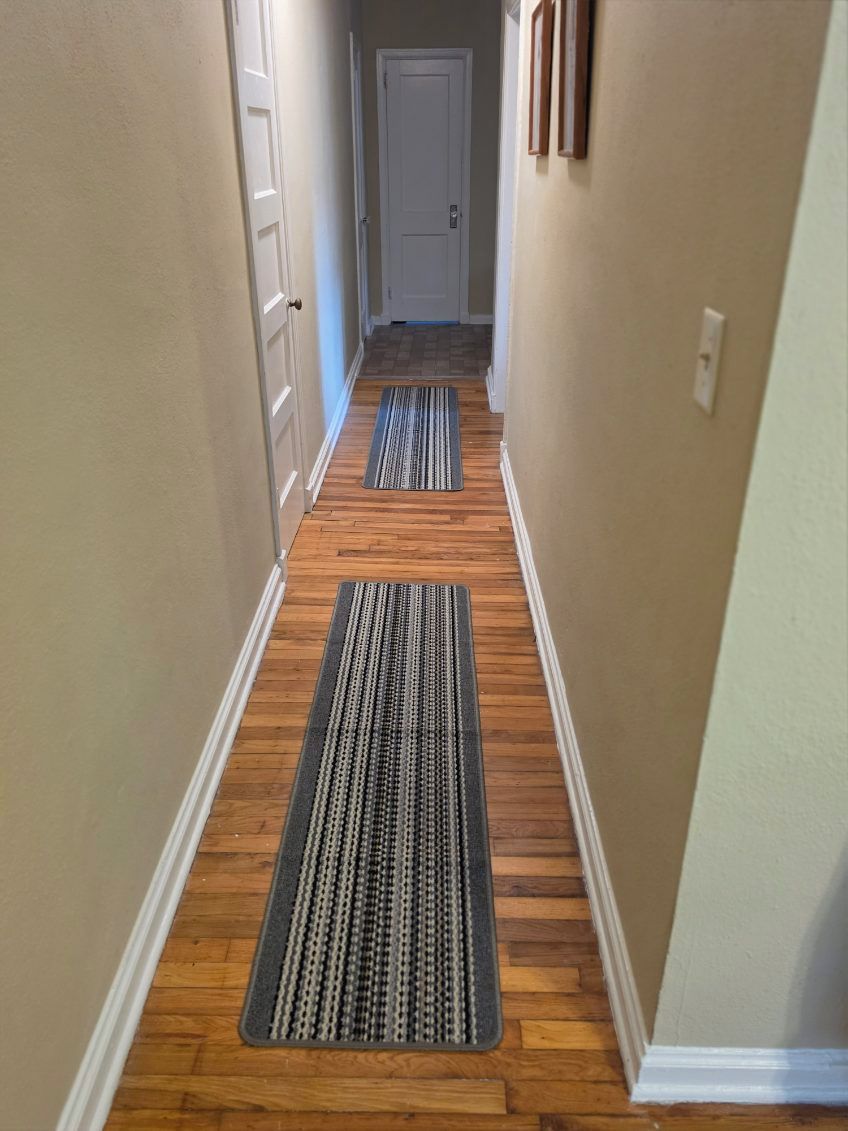 Un couloir doté d’un plancher en bois et de deux paillassons.