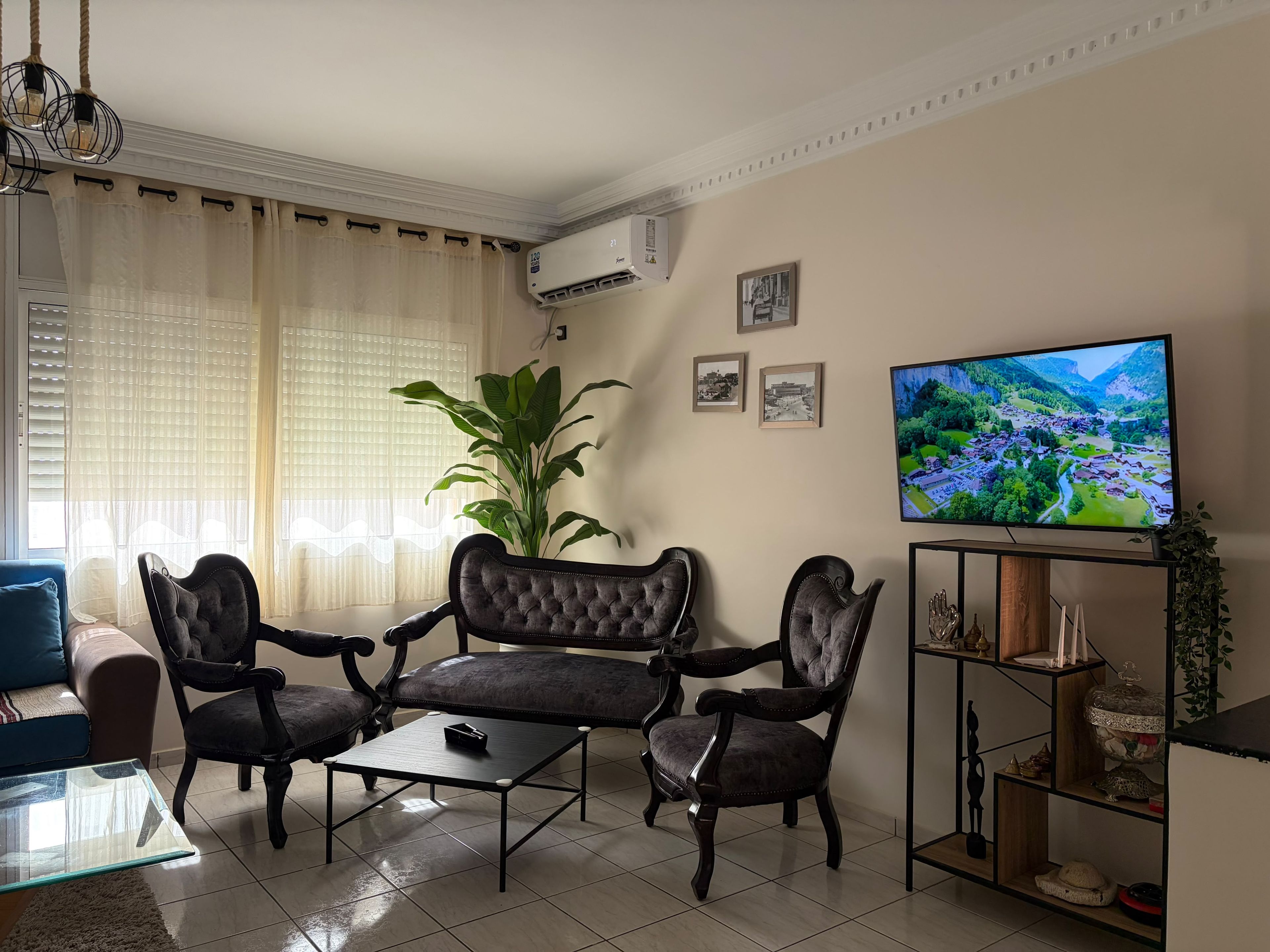 A living room with a sofa set, a coffee table, a television, and a potted plant.