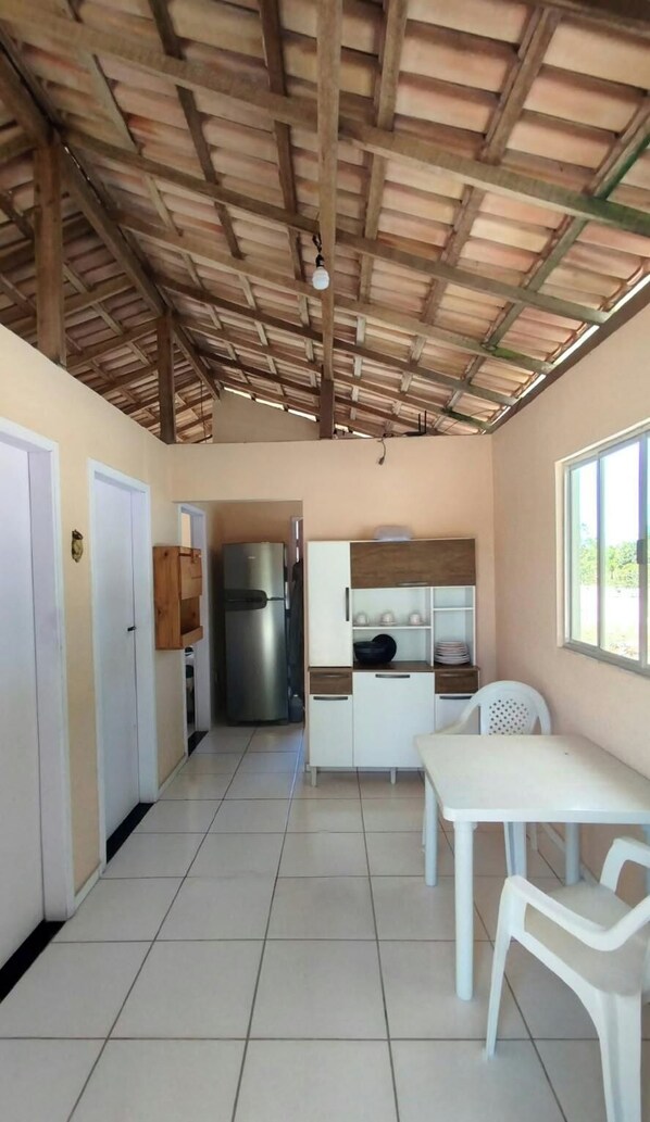 A kitchen with a tiled floor, a refrigerator, a sink, and a window providing natural light. - Morada Nascer do Sol. For a couple or a family. Close to Caraíva and Corumbau. (Brasilia)