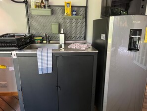 Eine kleine Küche mit Spüle, Kühlschrank und Mikrowelle.