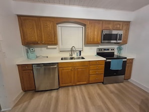 A kitchen with wooden cabinets, a stainless steel dishwasher, a microwave, and an oven. - Almosta Beach House  in Clearwater (Clearwater)