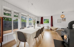 A modern interior with a dining area, a fireplace, and large windows. - 4 bedroom beautiful home in Hvide Sande (Hvide Sande)