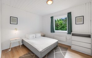 A bedroom with a bed, bedside tables, a window with curtains, a radiator, and a wardrobe. - 4 bedroom beautiful home in Hvide Sande (Hvide Sande)