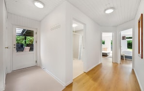 A hallway with white walls and wooden flooring, leading to a bedroom with a bed and a window. - 4 bedroom beautiful home in Hvide Sande (Hvide Sande)