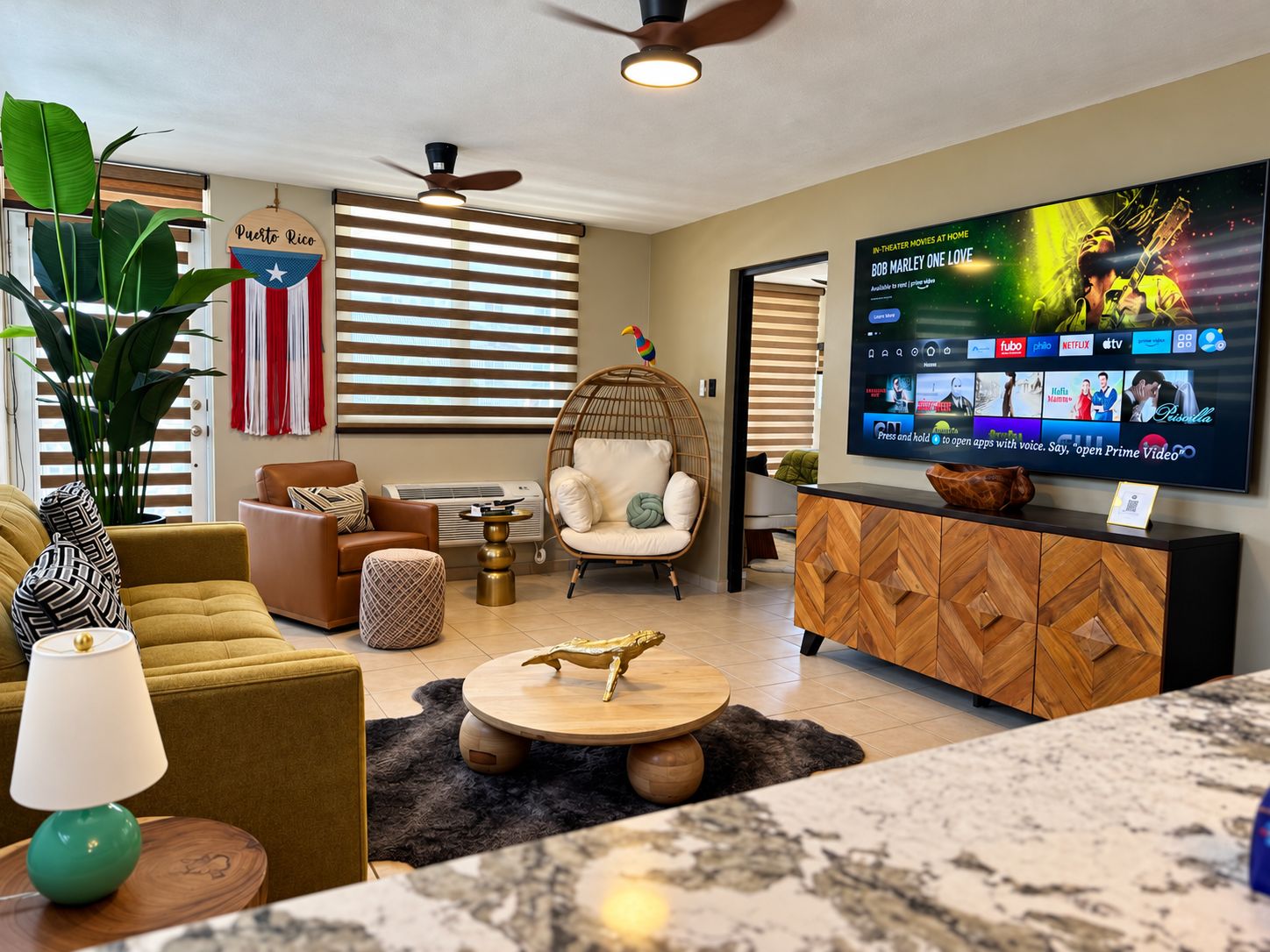 A modern living room with a flat-screen TV, comfortable seating, and a decorative plant.