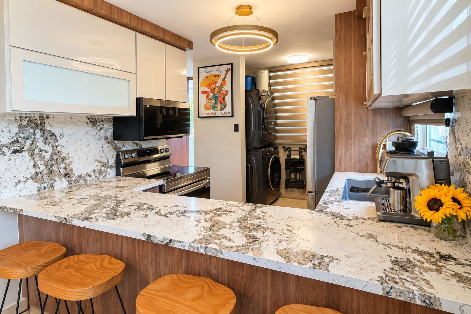 A modern kitchen with a marble countertop, stainless steel appliances, wooden bar stools, and a coffee machine.