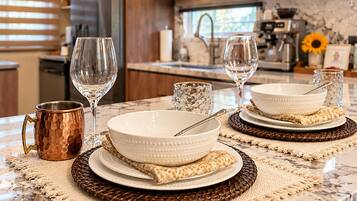 A kitchen counter with two white bowls, a copper mug, and two wine glasses.