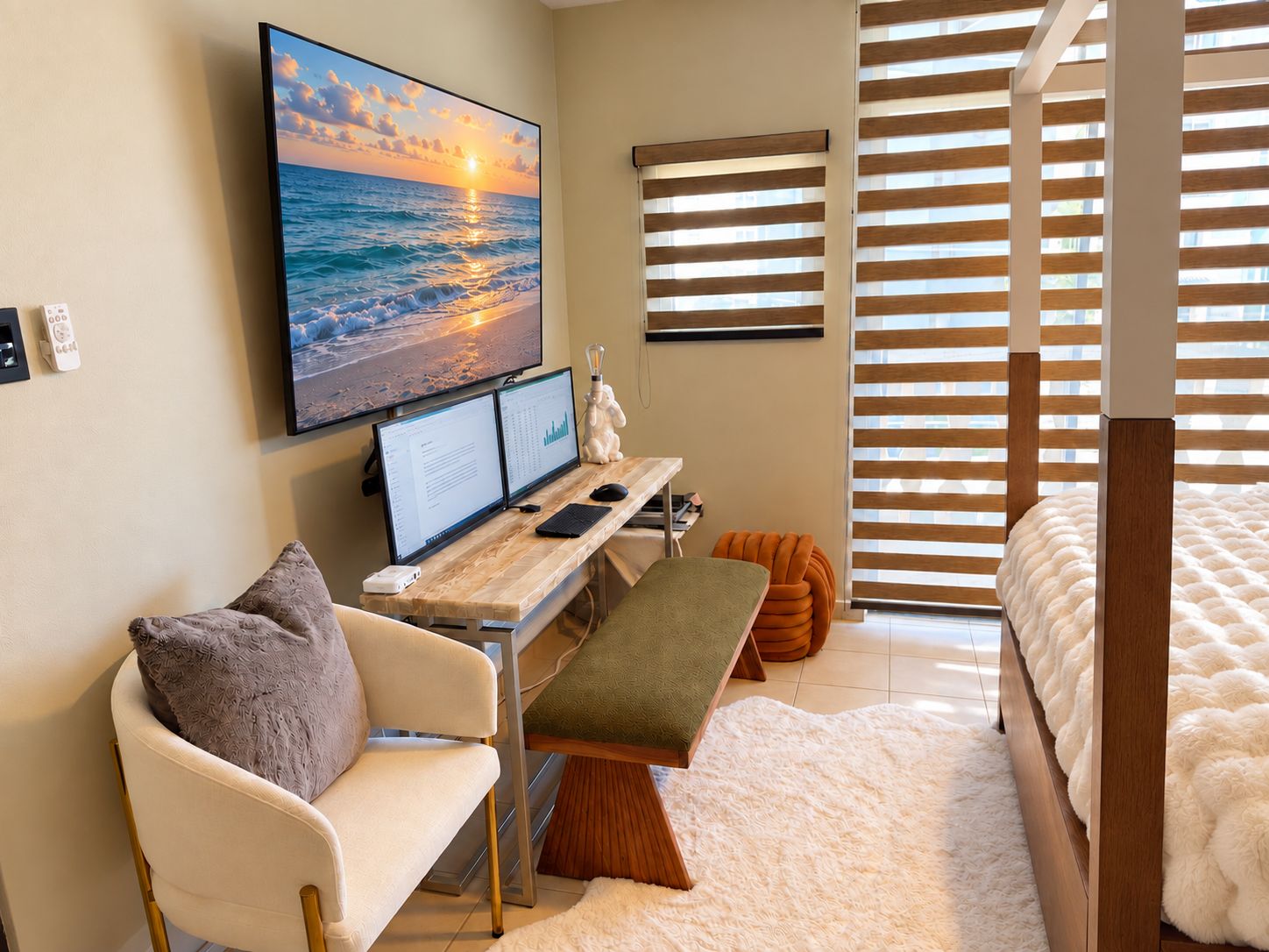 Une chambre à coucher moderne avec un lit, un bureau doté de deux écrans, un ordinateur portable et une grande fenêtre avec des stores.