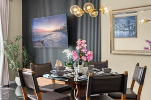 A dining area with a round table set for six, surrounded by chairs. - BREAKVIEW LUXE AT VISTA CAY | NEWLY RENOVATED ULTRA LUXURIOUS CONDO | MINUTES FROM UNIVERSAL (Orlando)