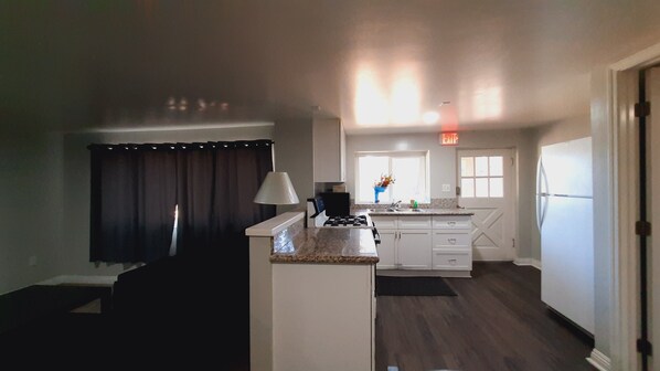 A modern kitchen with white cabinets, a granite countertop, and a black stove. - SHERWOOD ARMS MOTEL _CABIN #6 (Running Springs)
