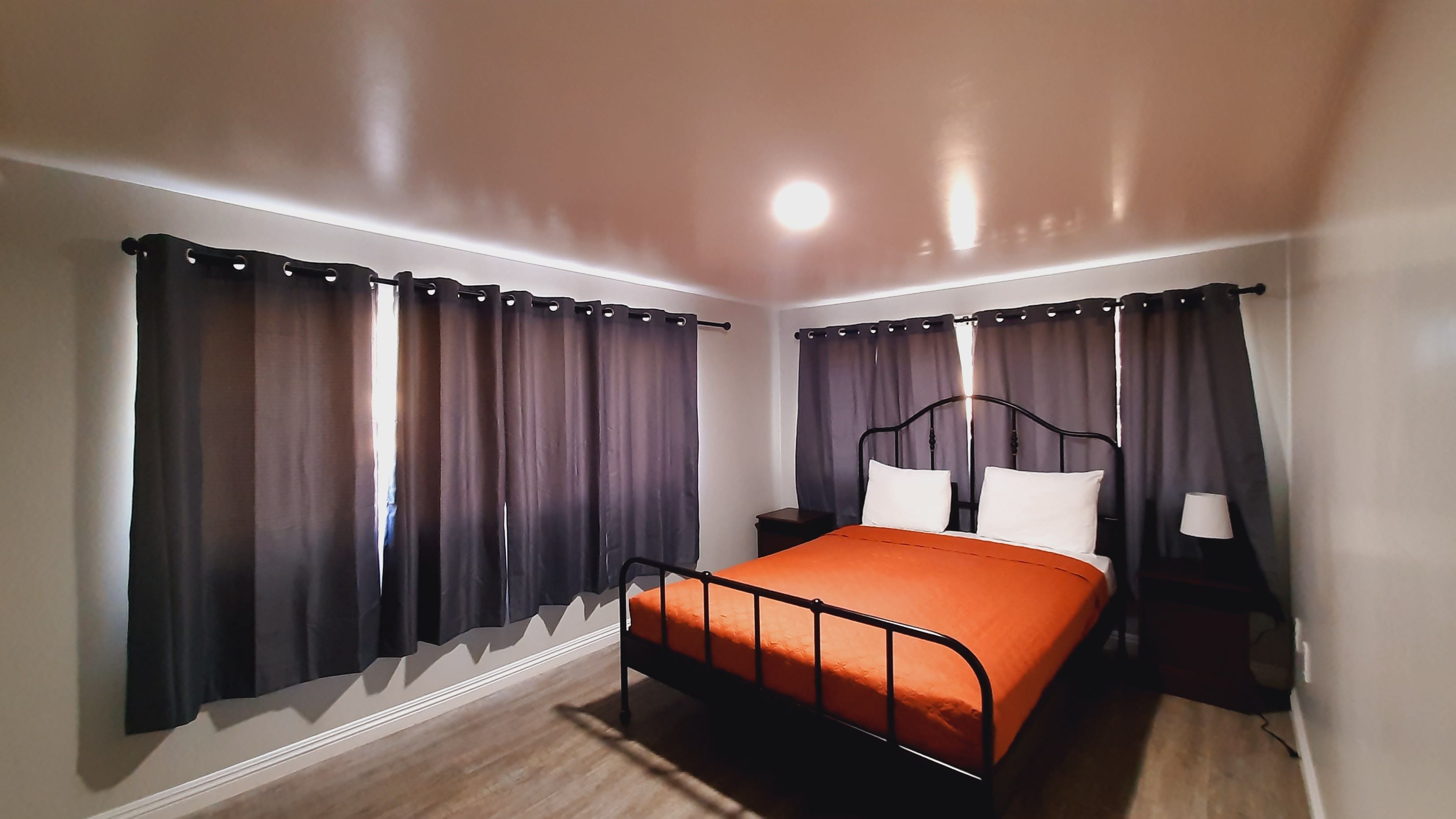 A bedroom with a bed, curtains, a nightstand, and a lamp.