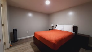 Ein Schlafzimmer mit einem Bett, einem Nachttisch, einer Lampe und einem Lautsprecher.