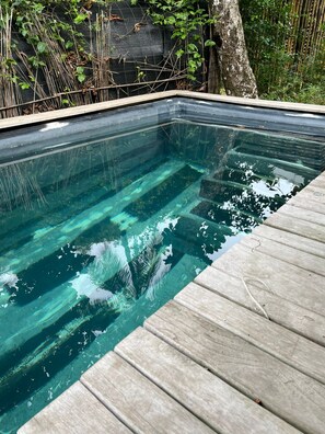 A clear swimming pool with a wooden deck edge.