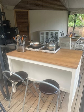A kitchen area with a wooden countertop, two bar stools, and a kettle.