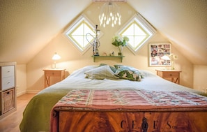A bedroom with a sloped ceiling, a bed with a patterned bedspread, two bedside tables with lamps, a wall-mounted shelf with decorative items, and a window with a view. - Stunning home in Sättra with WiFi (Sättra)