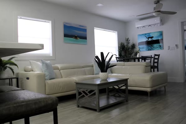 A living room with a beige sofa set, a coffee table, and a ceiling fan.