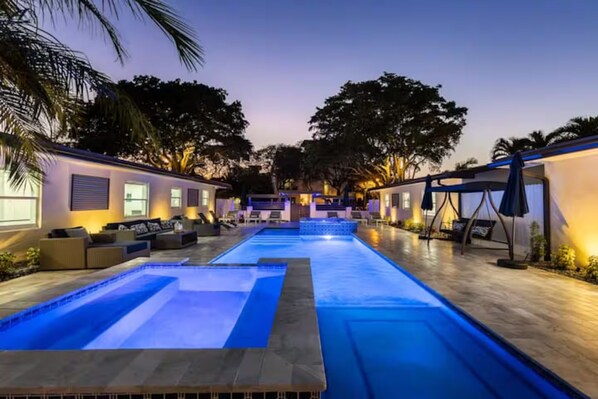 A swimming pool with a lounge area, outdoor seating, and a covered patio.