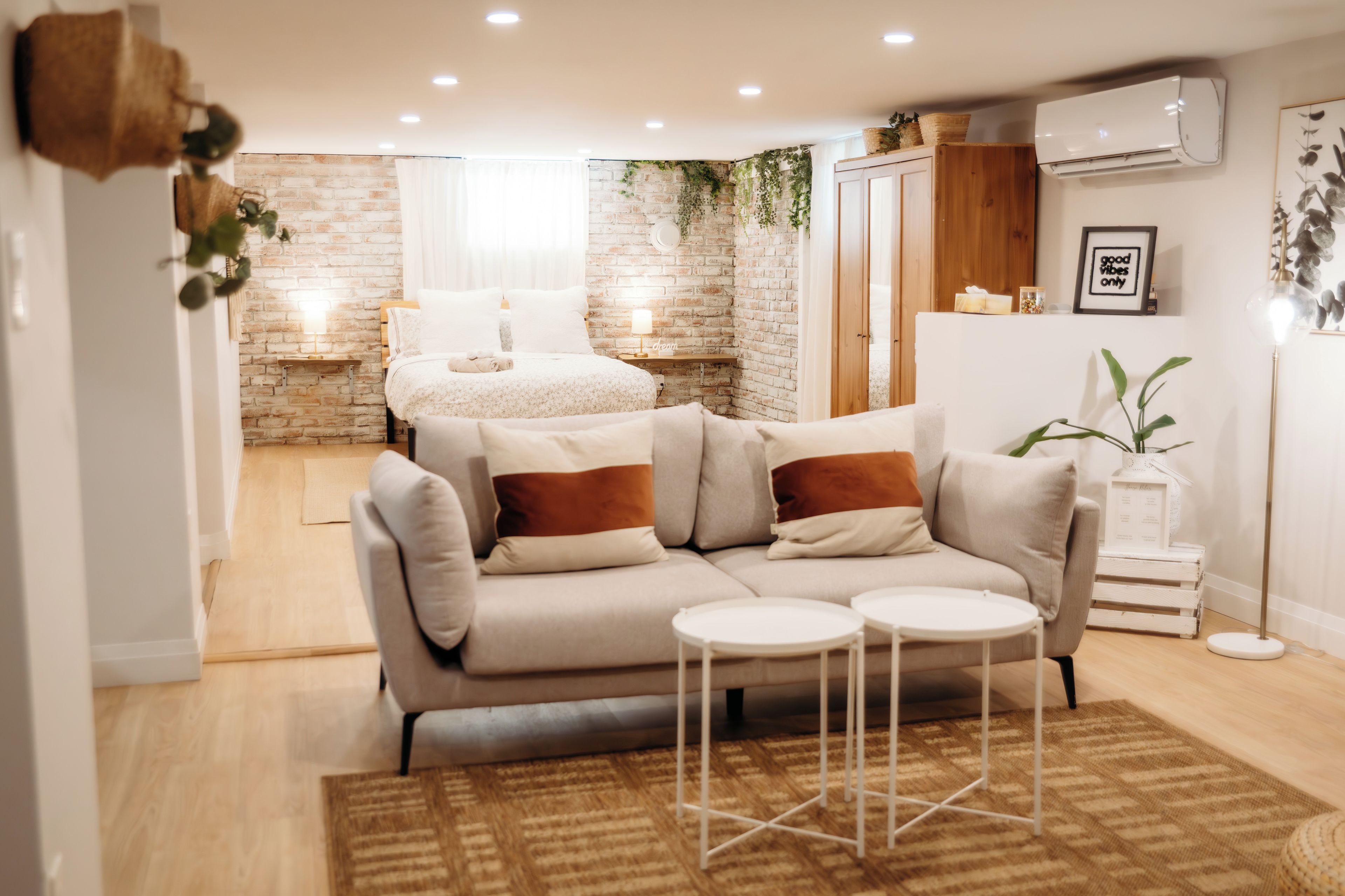A modern living room with a sofa, two side tables, a coffee table, a patterned rug, and a brick wall.