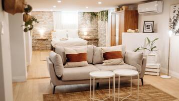 A modern living room with a sofa, two side tables, a coffee table, a patterned rug, and a brick wall.