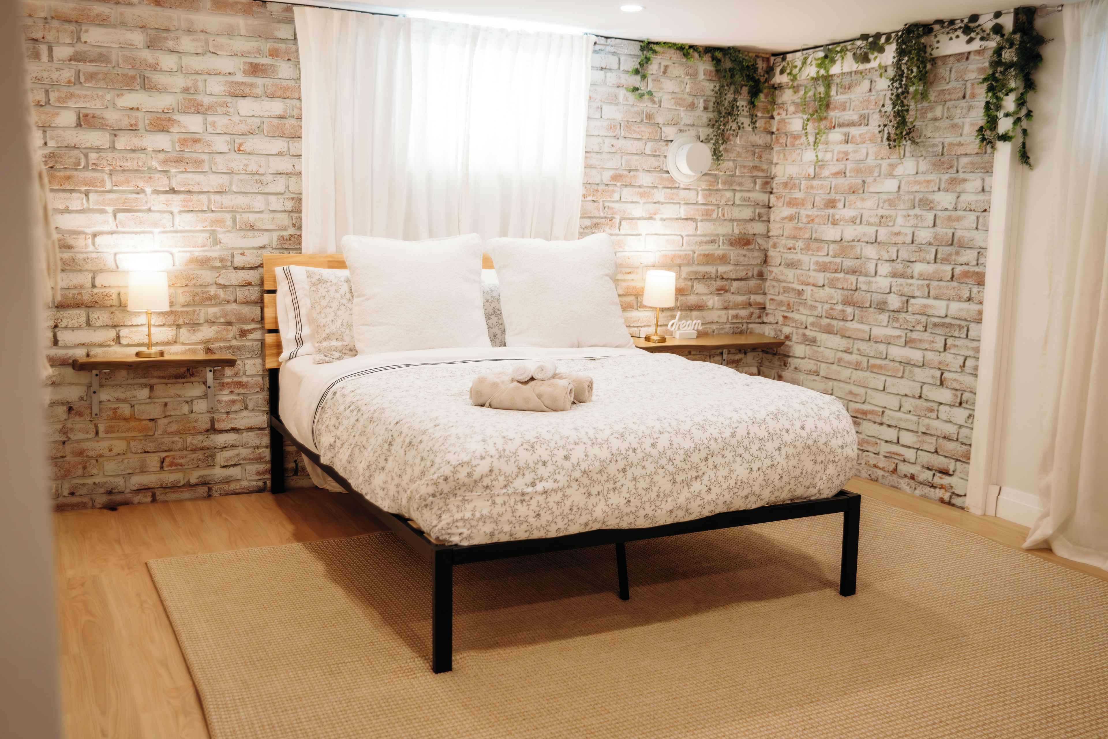 Una cama con colcha estampada, dos lámparas de noche y una alfombra pequeña.