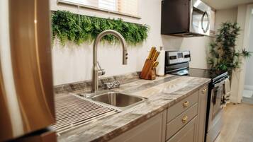 A kitchen with a stainless steel sink, wooden countertop, and a built-in microwave.