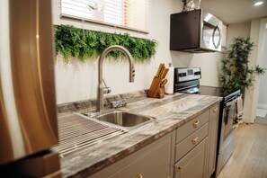 Una cocina con un lavamanos de acero inoxidable, encimera de madera y un microondas empotrado.