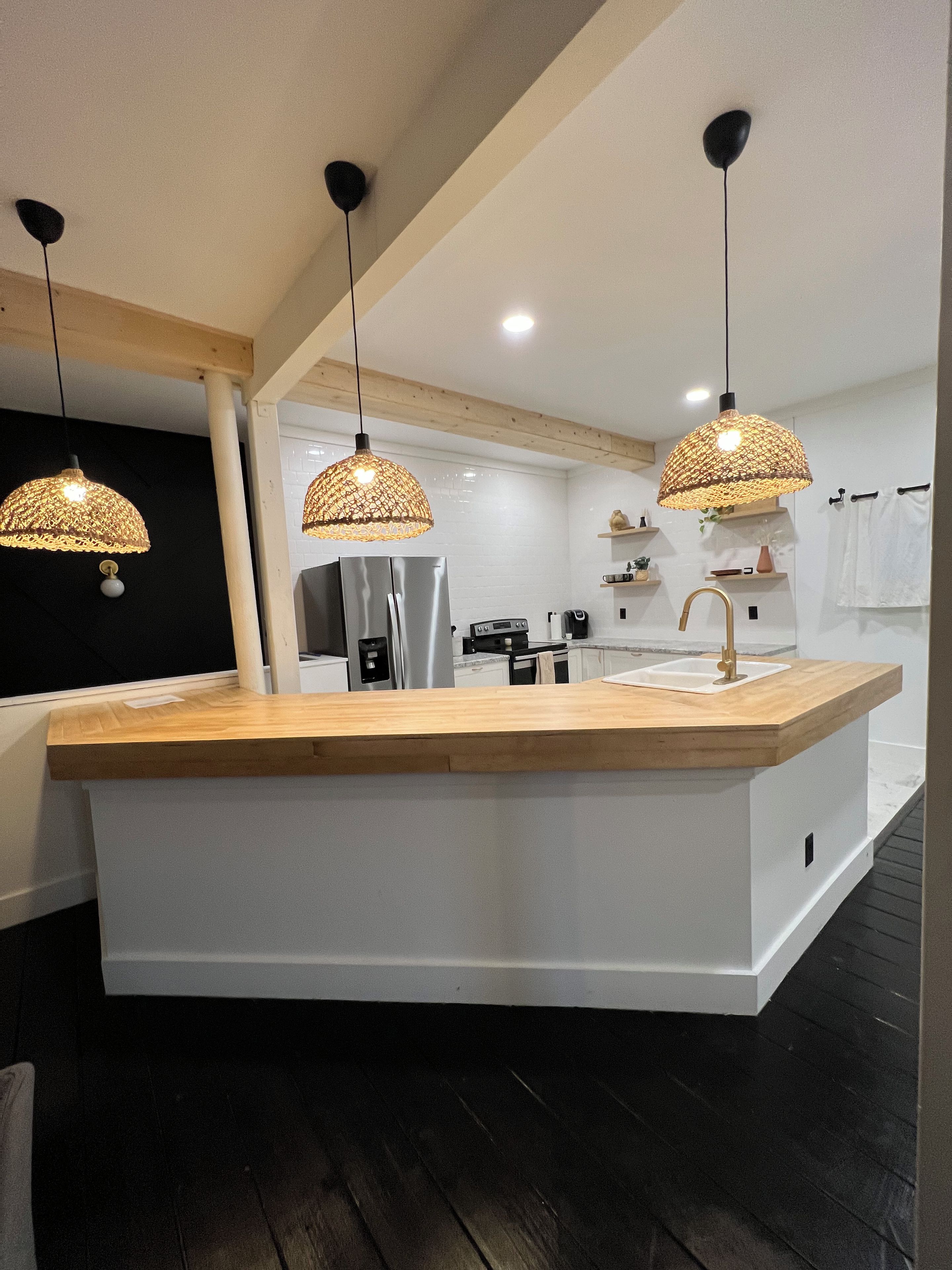 Una cocina moderna con una isla central, iluminación colgante y un refrigerador integrado.