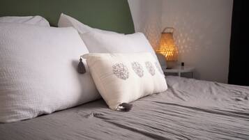 Una cama bien hecha con almohadas blancas y un cojín decorativo con flecos.