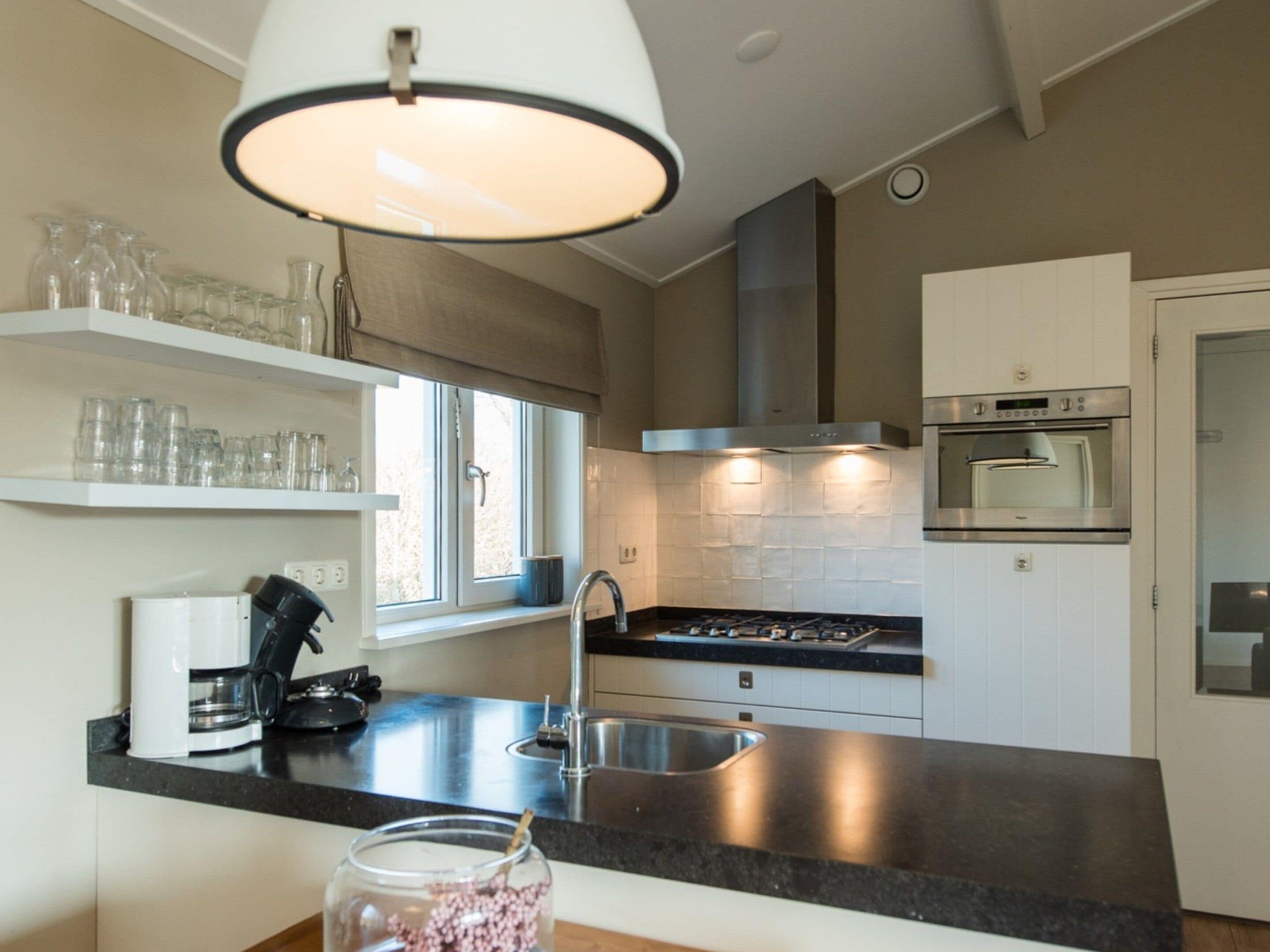 A modern kitchen with a gas stove, stainless steel appliances, and a window with a view.