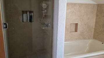 Un bagno con doccia vetro, vasca e WC.