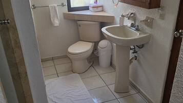 Un baño pequeño y limpio con inodoro, lavabo y ventana.