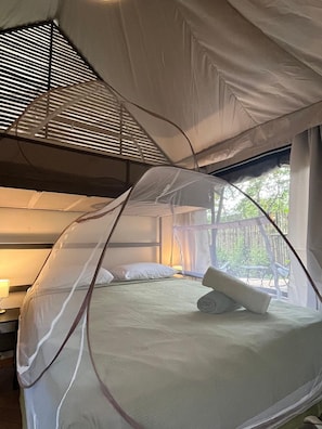 A tented accommodation with a bed, a pillow, and a rolled towel.