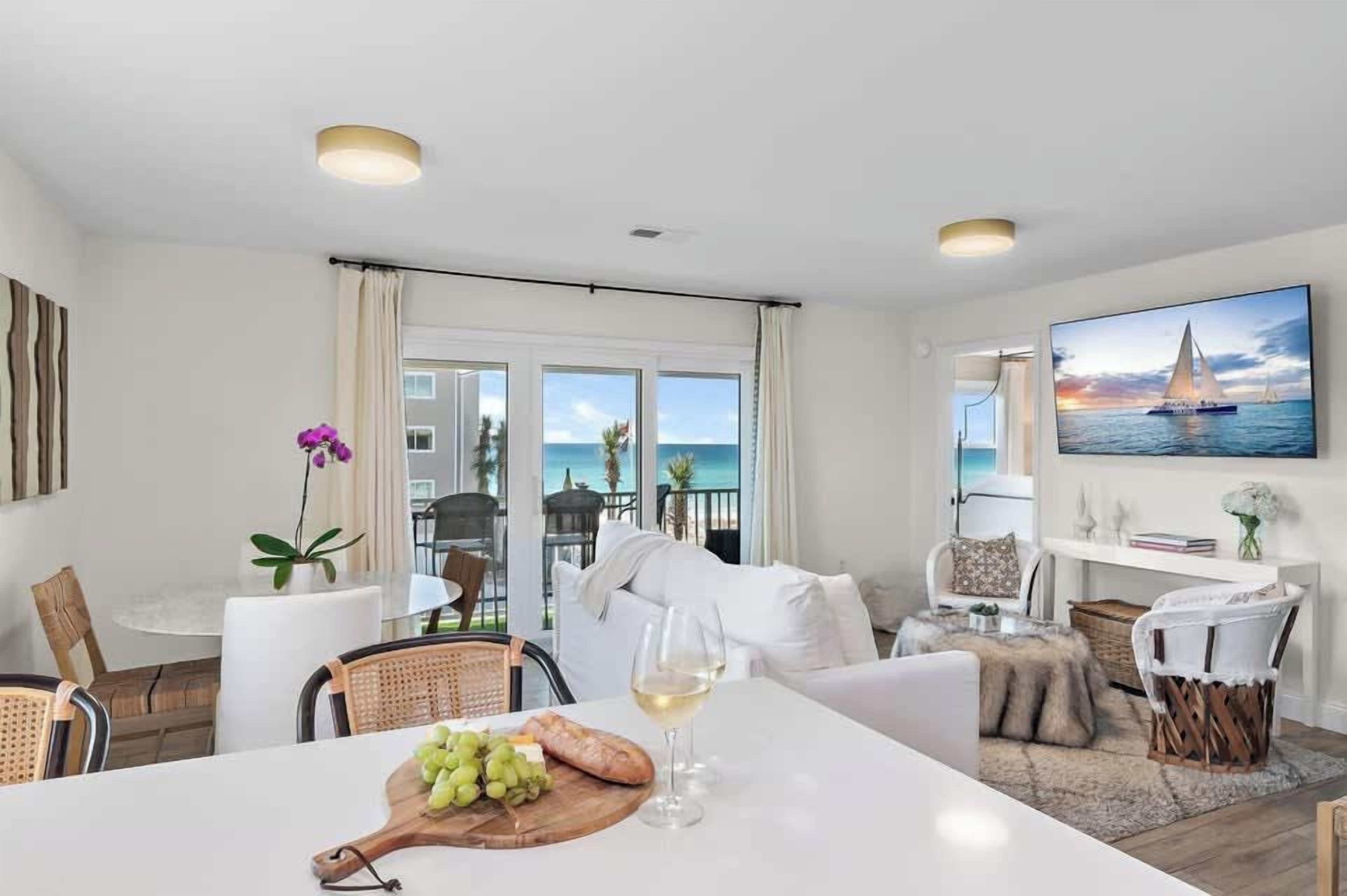 A modern living room with a dining area, a television, and a view of the sea.