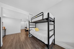 A bunk bed room with a desk and chair, white walls, and wooden flooring. - Down Under Loft · Bunk Studio for Riders (Bella Vista)