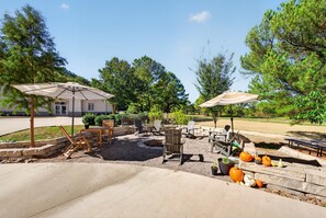 An outdoor patio area with seating and umbrellas, surrounded by trees and a building in the background. - Silent Hattie Loft · Studio by Tunnel Vision Trail (Bella Vista)
