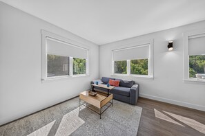 A modern living room with a grey sofa, a wooden coffee table, and a patterned rug. - Silent Hattie Loft · Studio by Tunnel Vision Trail (Bella Vista)