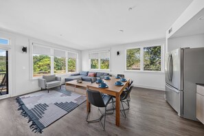 A modern kitchen with a dining area, large windows, and a built-in refrigerator. - Play Thru Loft · 2BR w/ Balcony Near Back 40 (Bella Vista)