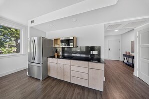Eine moderne Küche mit einem Edelstahl-Kühlschrank, Holzschränken und einer schwarzen Arbeitsplatte.