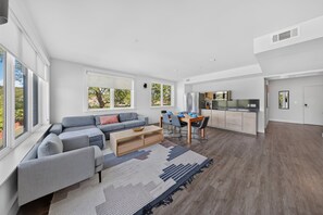 A modern living space with a sofa, coffee table, and dining area. - Play Thru Loft · 2BR w/ Balcony Near Back 40 (Bella Vista)