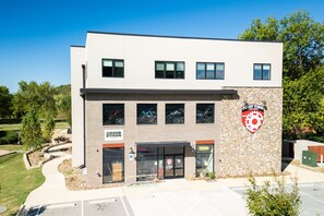 A building with a sign for 'PHATTIRE BIKE SHOP' and 'GRINDSTONE COFFEE'. - Staggerwing Loft · 2BR Above Bike Shop & Café (Bella Vista)