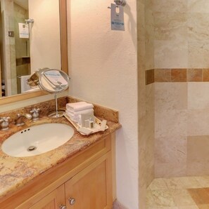 A bathroom with a marble sink, a mirror, a towel rack, and a shower area. -  Ocean Front Spacious 2-bedroom condo in Cabo San Lucas with view of Lands End. (Cabo San Lucas)