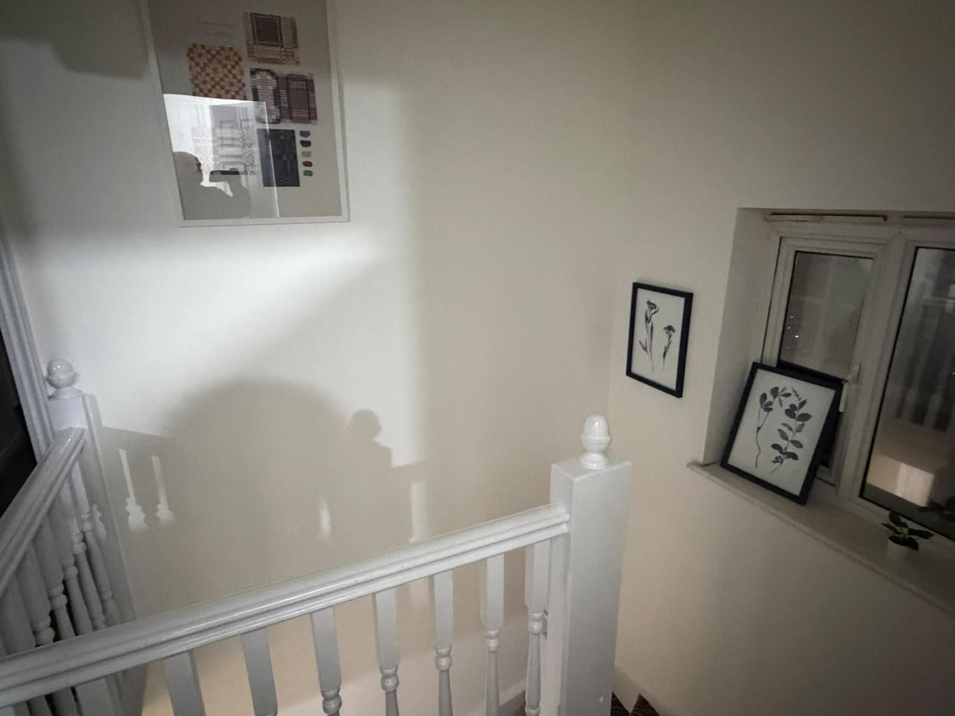 A staircase with a white railing, a wall-mounted picture frame, and a window with a view.